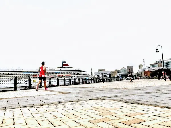 みなとみらい赤レンガ倉庫広場をジョギングする人物画像